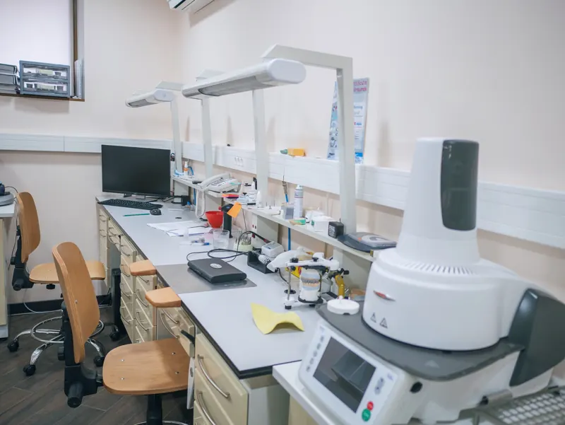 Dental laboratory workspace with technician benches and a lab scanner